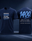 Two light blue short-sleeve T-shirts shown front and back on a blue studio background. The front has white text reading 'WHEREVER I MAY ROAM, THE ROAD LEADS HOME.