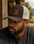 Man wearing a customizable trucker hat with a leather patch in an outdoor setting
