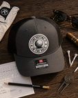 Dark gray trucker golf hat with black mesh, circular logo patch, and Richardson 112 tag