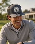 Charcoal gray trucker golf hat with black mesh sides and circular 'I Like Putting' patch