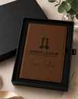 Brown leather notebook with engraved text in a black box on a light surface.