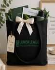 Black tote bag with Junior League Palo Alto/Mid Peninsula branding, filled with stationery items on a wooden surface.