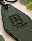Macro close-up of laser engraved Junior League logo on green vegan leather motel keychain with detailed stitching