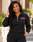 Black woman modeling a black ladies Delta Sigma Theta quarter-zip sweatshirt