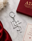 Delta Sigma Theta DST monogram silver keychain with lobster clasp on marble surface next to crimson gift box