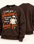 A dark brown crewneck sweatshirt shown from both front and back. The front features a graphic of a cartoon ghost wearing sunglasses with the text 'I told you ghosting me would come back to haunt you' in orange and white lettering.