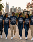 Six people walking hand in hand outdoors in matching navy blue jackson state nashville tiger takeover t-shirts against a city skyline with a Nissan Stadium background.
