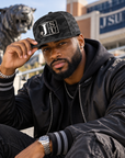 Black man modeling Jackson State Black Camo New Era 9FIFTY flat bill snapback with Block JSU patch