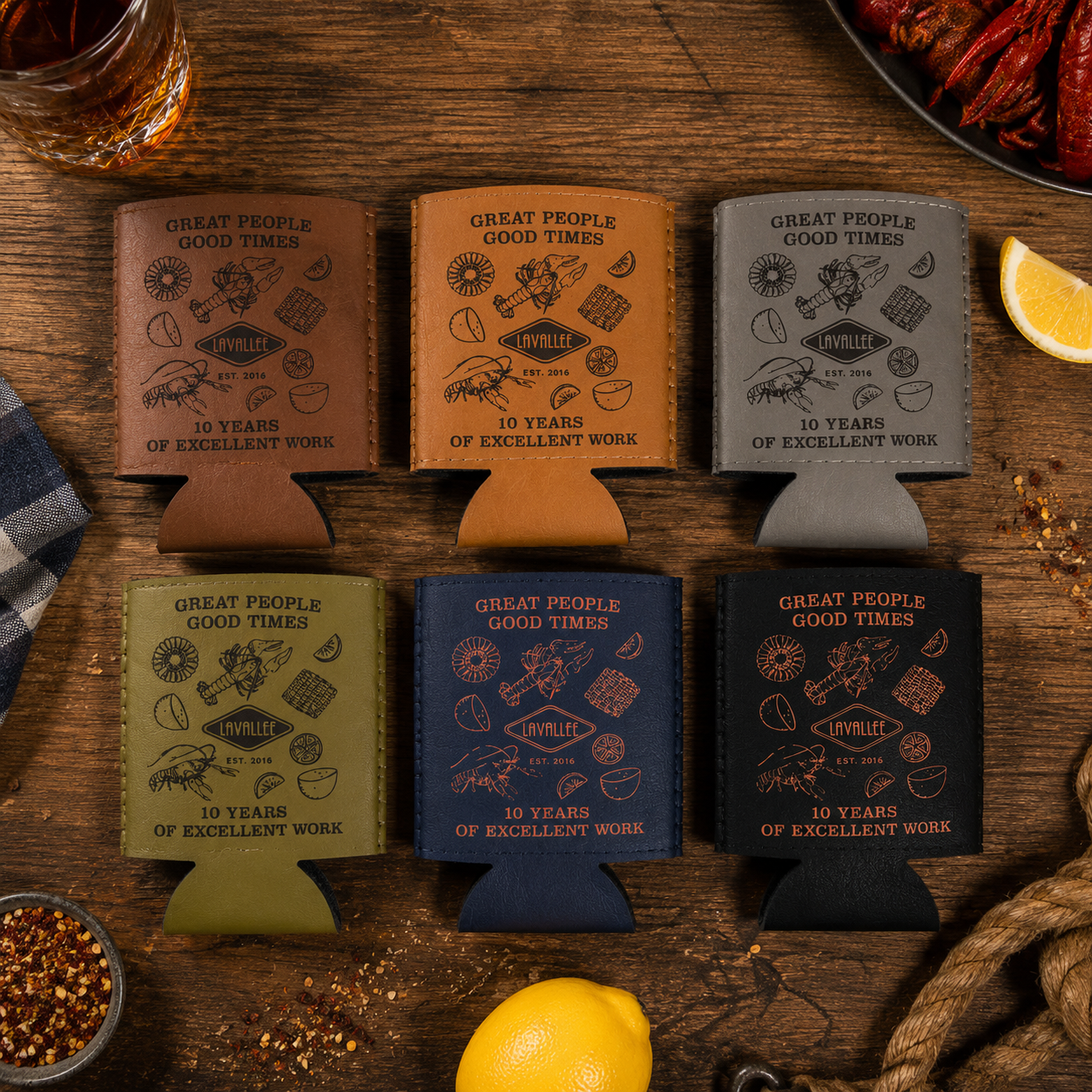Premium flat lay of LaVallee anniversary crawfish boil koozies in assorted leatherette and neoprene colorways arranged in a clean editorial retail presentation.