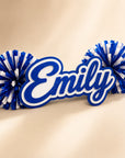 Personalized three-layer acrylic name spirit stick from the Classic Collection with coordinating pom-poms displayed on a luxury ivory background.