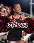 African American high school cheerleader holding a personalized acrylic mascot spirit stick in football stadium bleachers during a Friday night game.