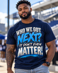 Black man wearing navy Who We Got Next It Don't Even Matter T-shirt at a game-day stadium setting
