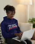 Navy unisex pullover hoodie with “Alumni” chest logo, worn by a seated person