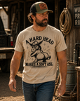 Man wearing sand colored A Hard Head Makes a Soft Ass western graphic t-shirt outdoors
