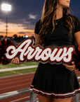 Personalized acrylic spirit stick with cursive red-and-white text and red pom-poms