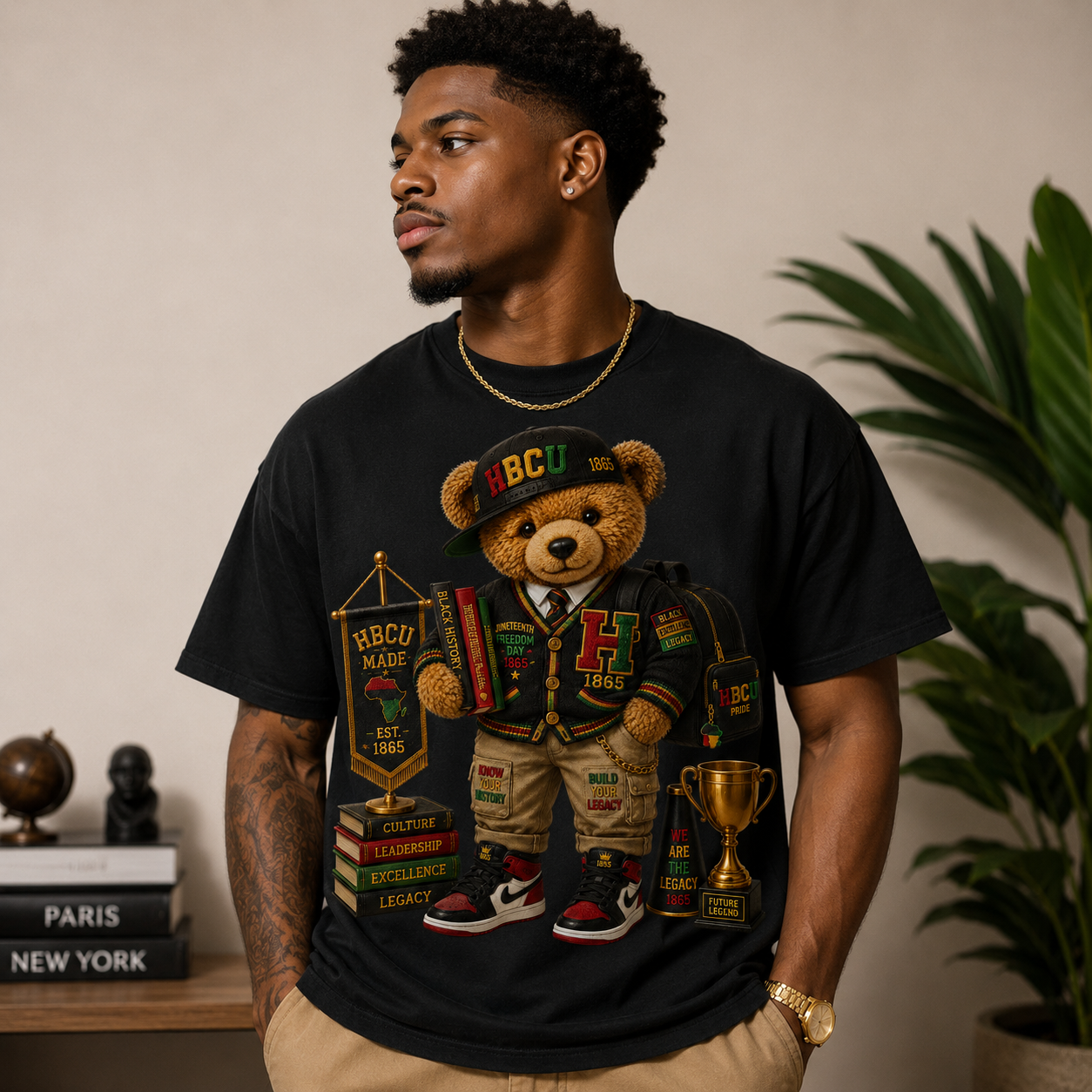 Black T-shirt with teddy bear graphic in an HBCU hat, holding a small trophy badge