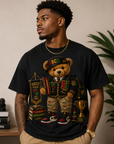 Black T-shirt with teddy bear graphic in an HBCU hat, holding a small trophy badge