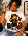 White T-shirt with teddy bear graphic in a cap, holding a ball and showing Juneteenth badges