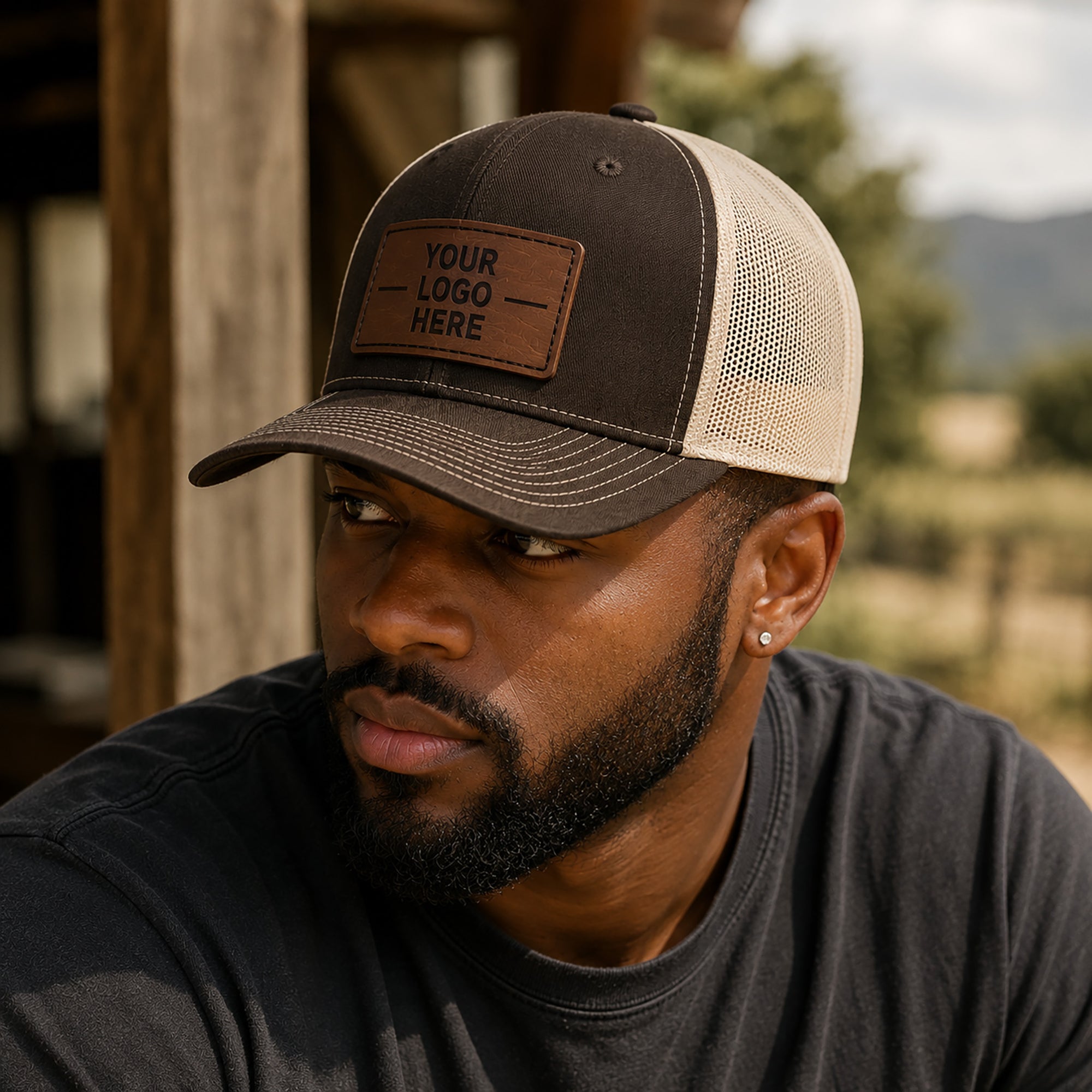 Man wearing a customizable trucker hat with a leather patch in an outdoor setting