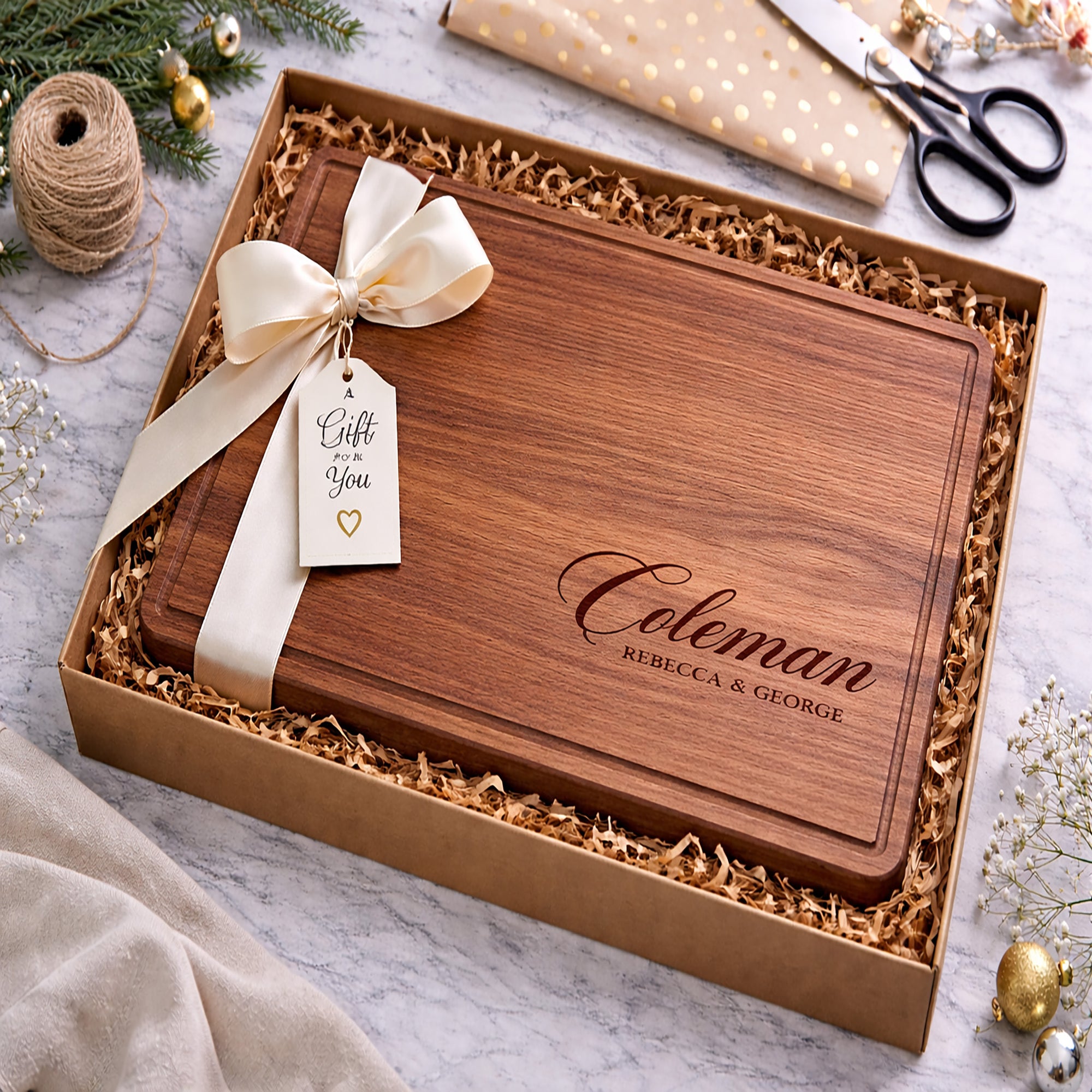 Wooden cutting board with engraved name in a gift box with ribbon and tag.