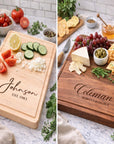 Two wooden cutting boards with engraved names and food items on a marble surface.