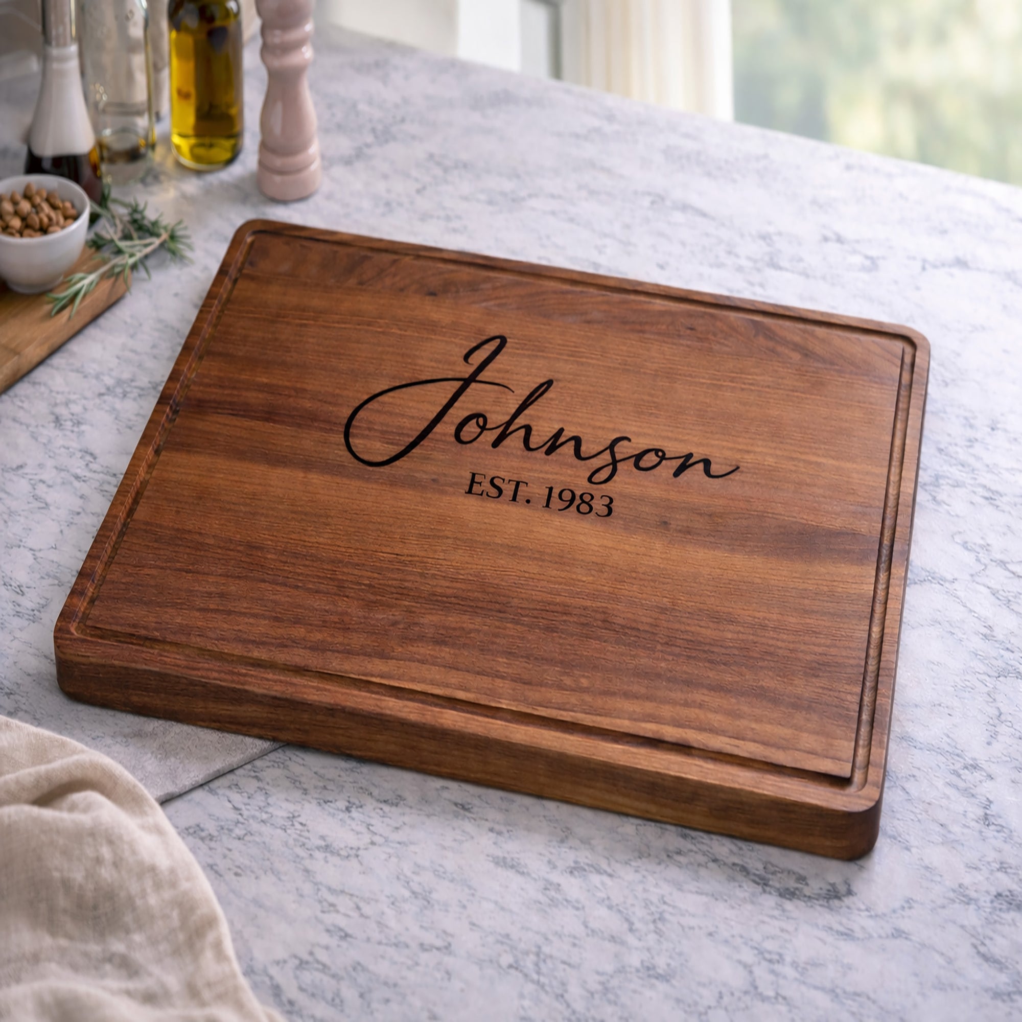 Wooden cutting board with 'Johnson EST. 1983' engraving on a marble countertop.