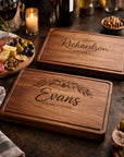 Two wooden cutting boards with engraved text on a table with food and wine.