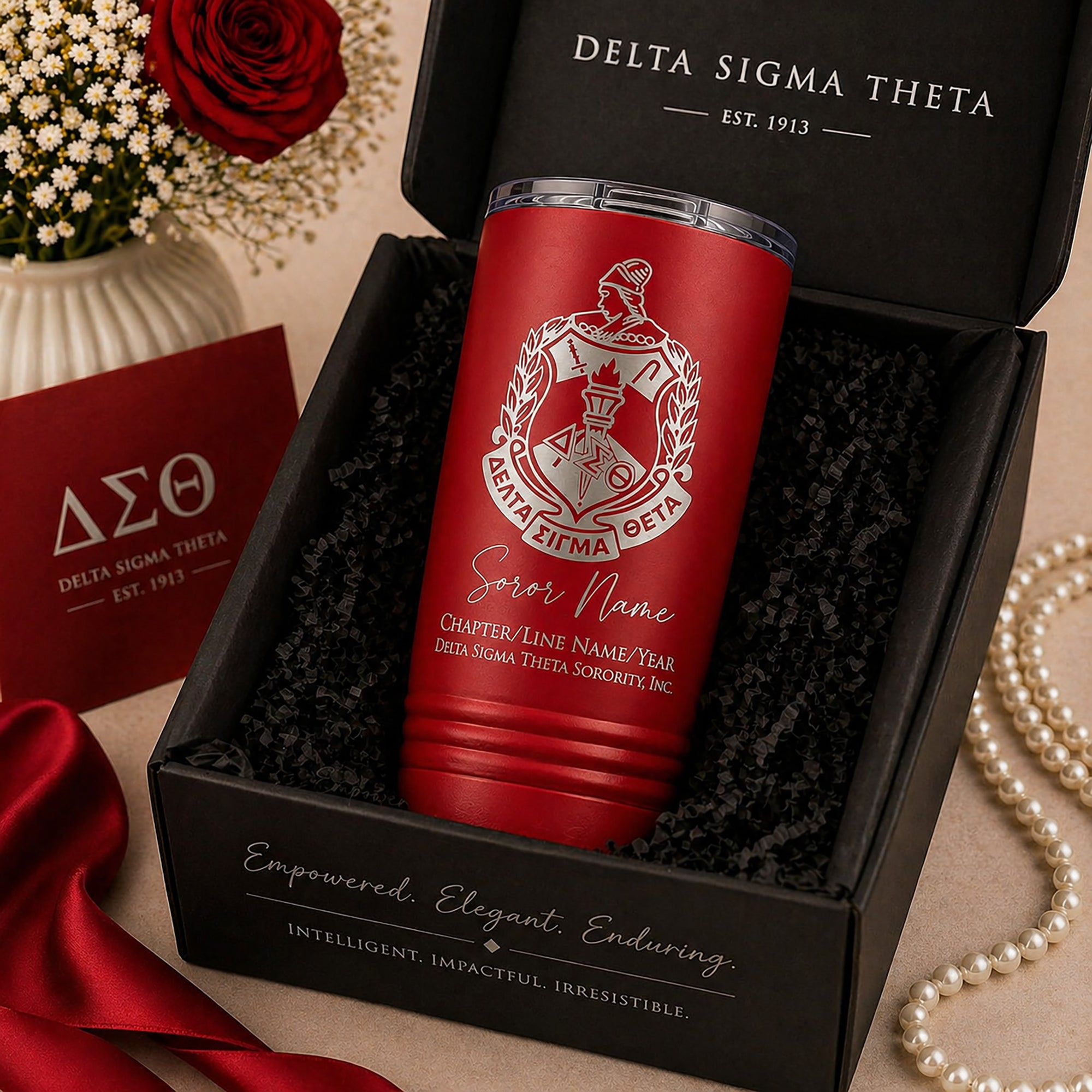 Red tumbler with Delta Sigma Theta logo in a gift box, surrounded by decorative items.