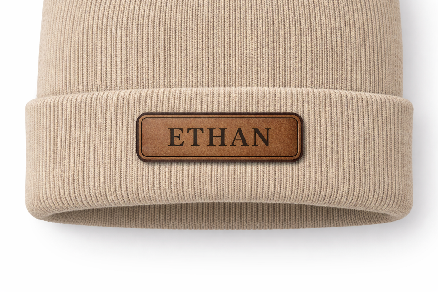 Beige beanie with a brown leather patch displaying 'ETHAN' on a white background