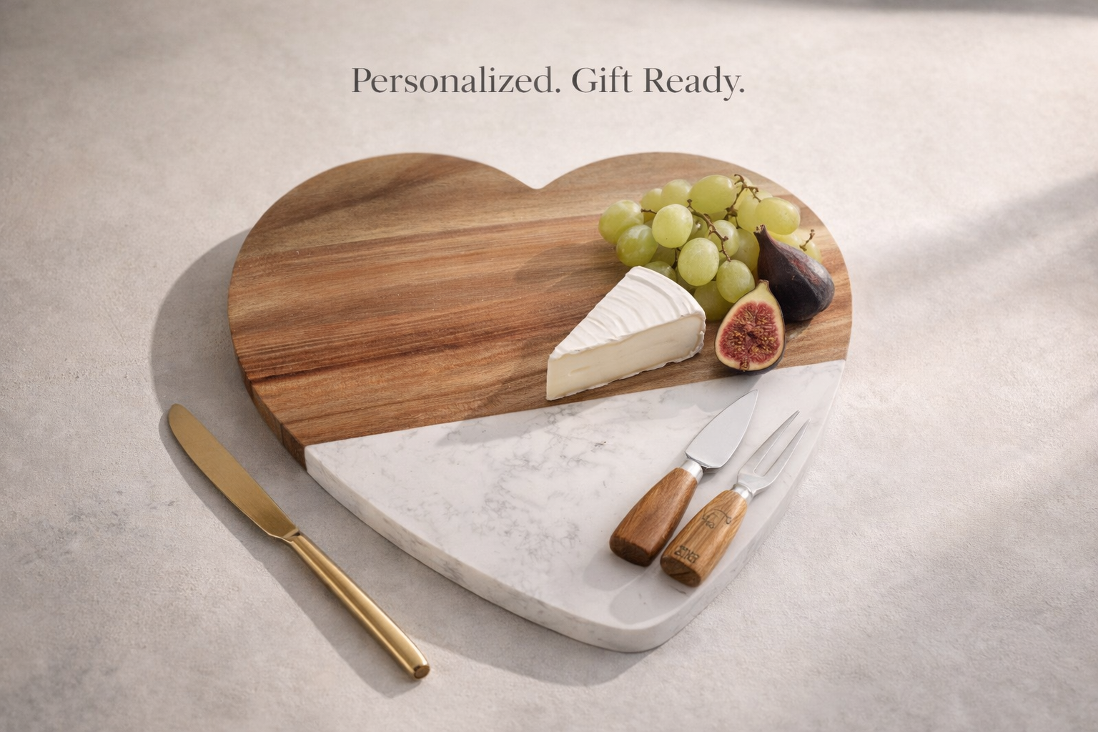 Heart-shaped cutting board with cheese, grapes, and figs on a marble surface with a knife.