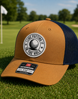 Caramel and navy trucker golf hat with brown front panel and circular 'I Like Putting' patch