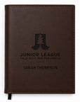 Brown leather notebook with engraved text and logo on a white background