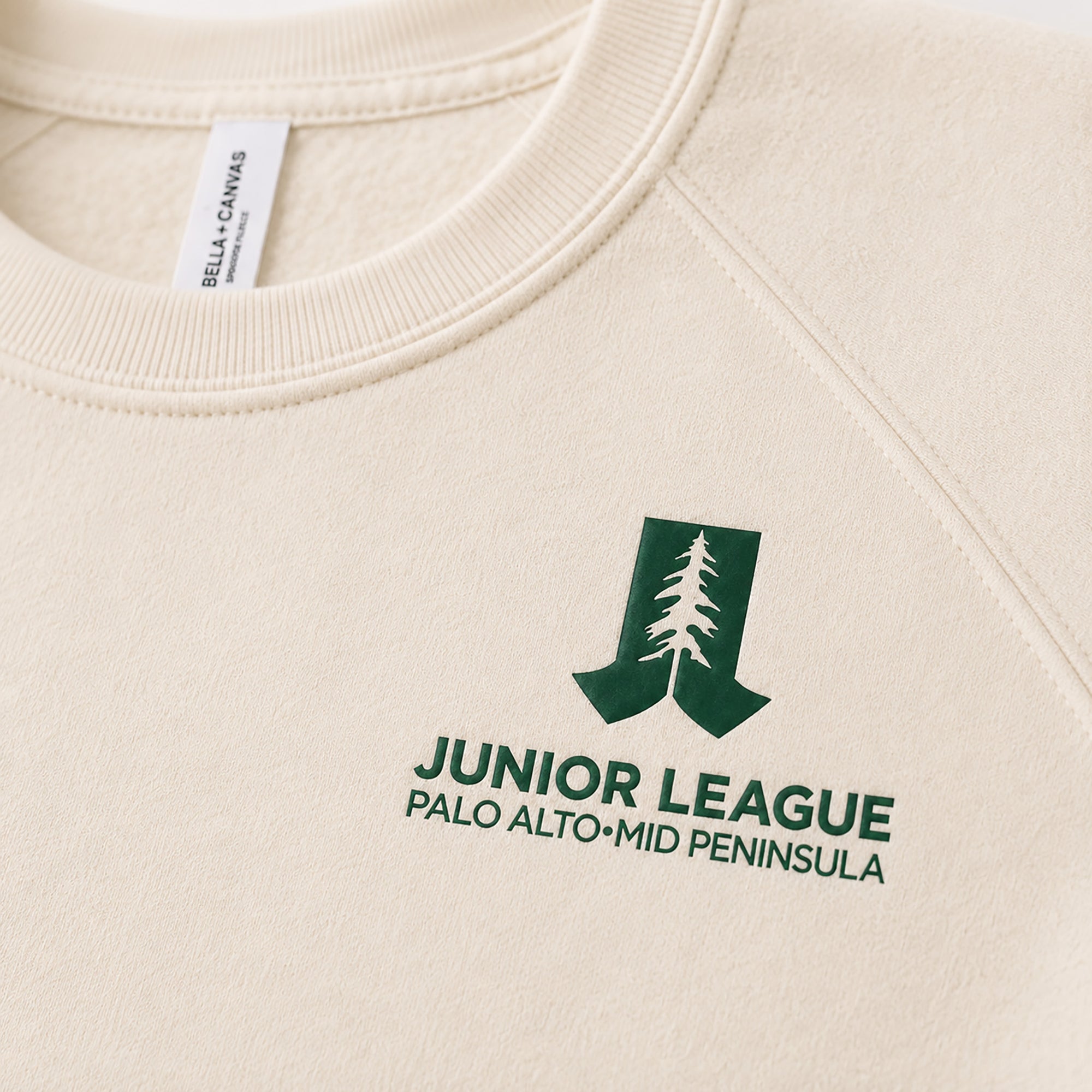 Close-up of green chest logo on natural raglan sweatshirt