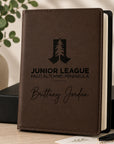 Brown notebook with engraved text and logo on a wooden surface