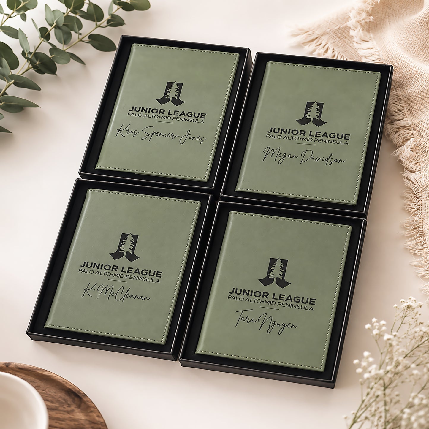 Four green name cards with 'Junior League' logo and names on a white surface with decorative elements.