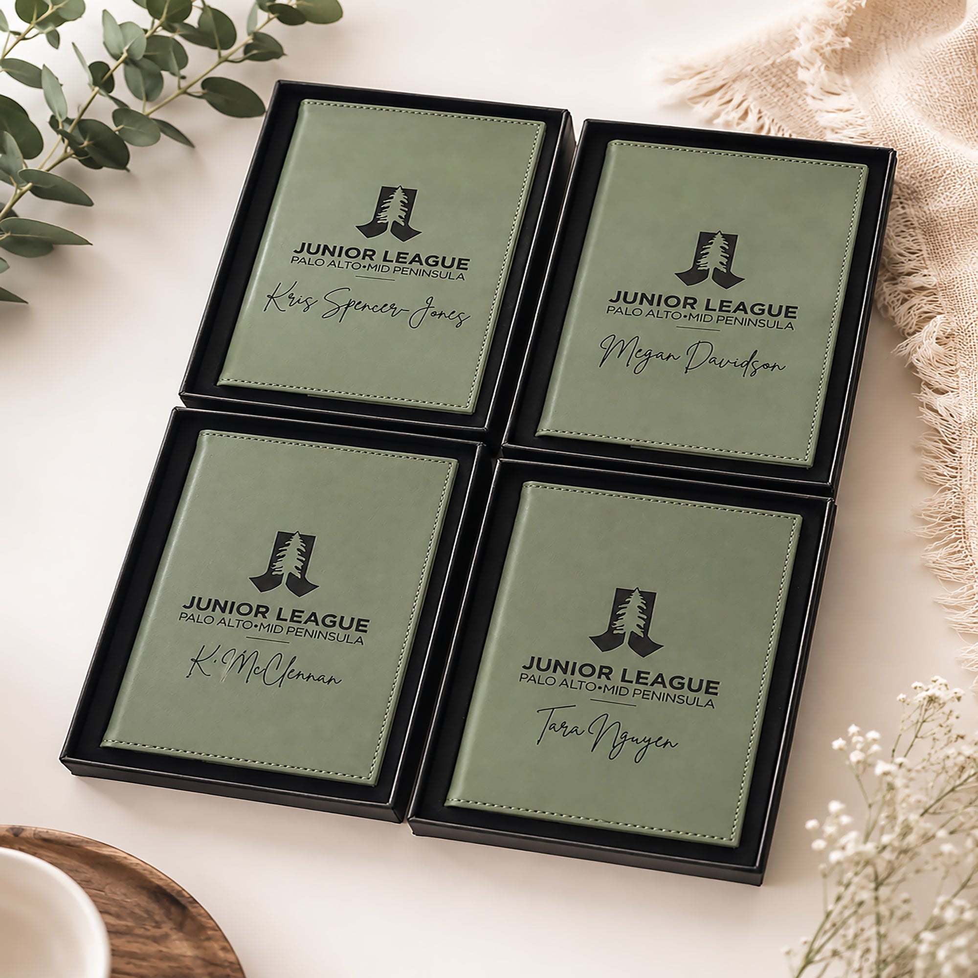 Four green name cards with 'Junior League' logo and names on a white surface with decorative elements.