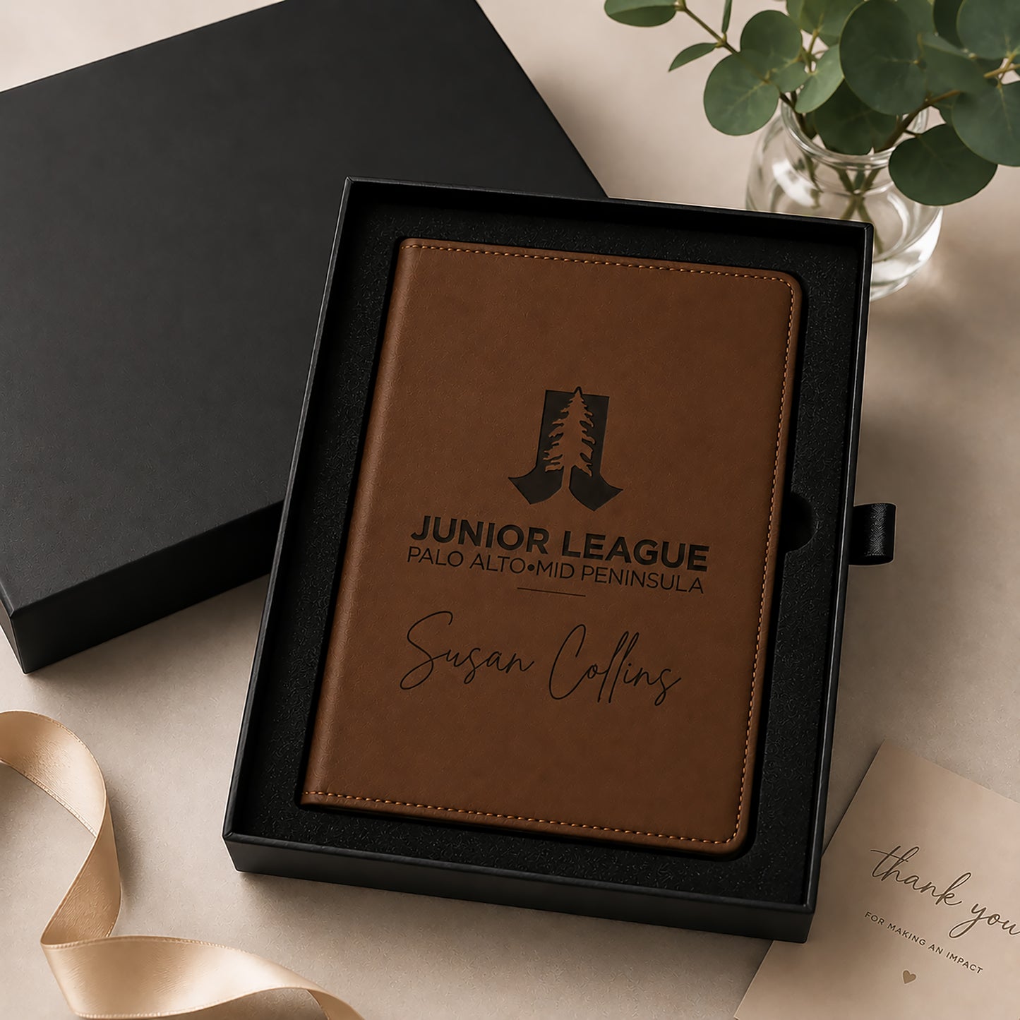 Brown leather notebook with engraved text in a black box on a light surface.
