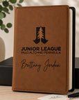 Brown notebook with engraved text and logo on a wooden surface