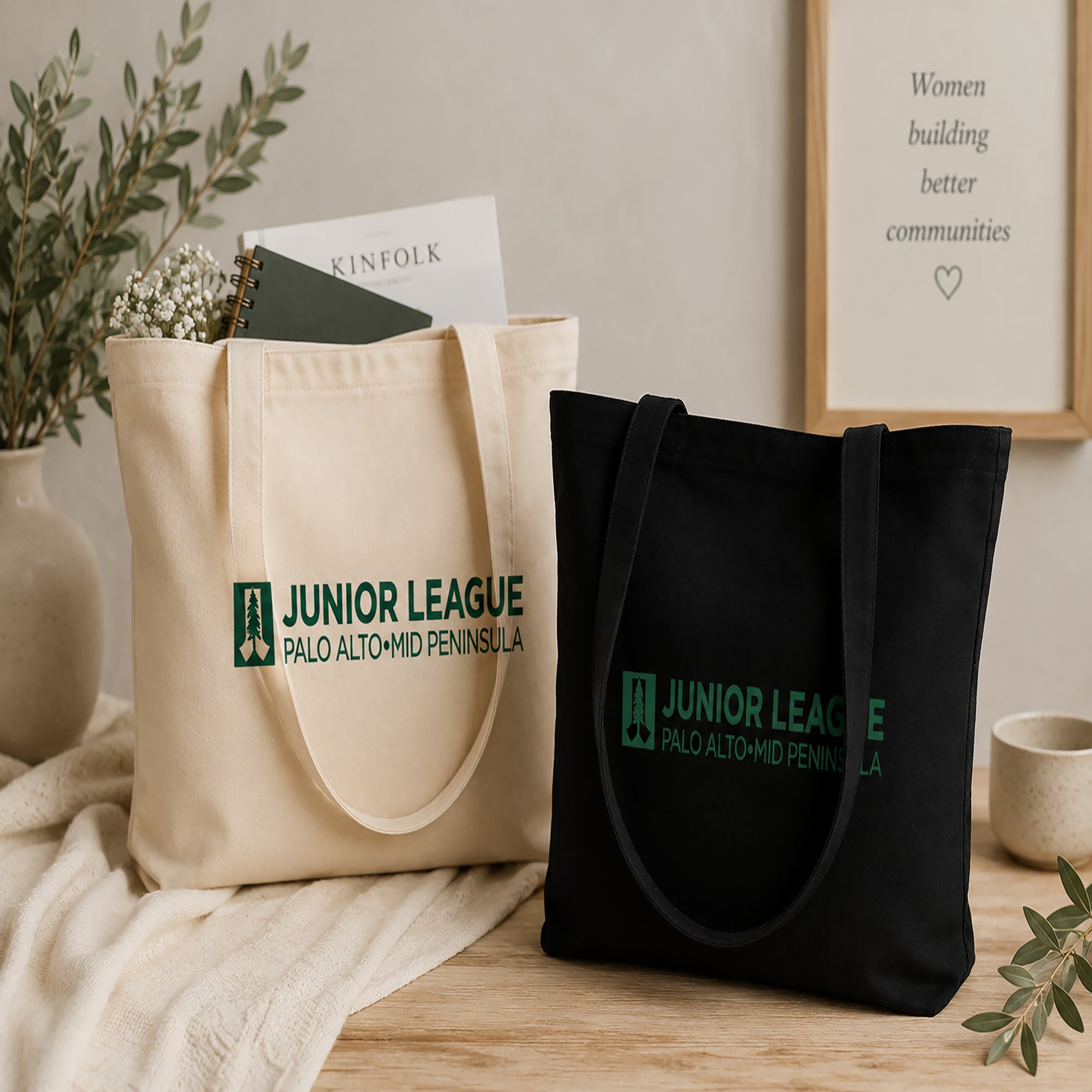 Natural and black tote bags with Junior League Palo Alto-Mid Peninsula logo on a wooden surface.