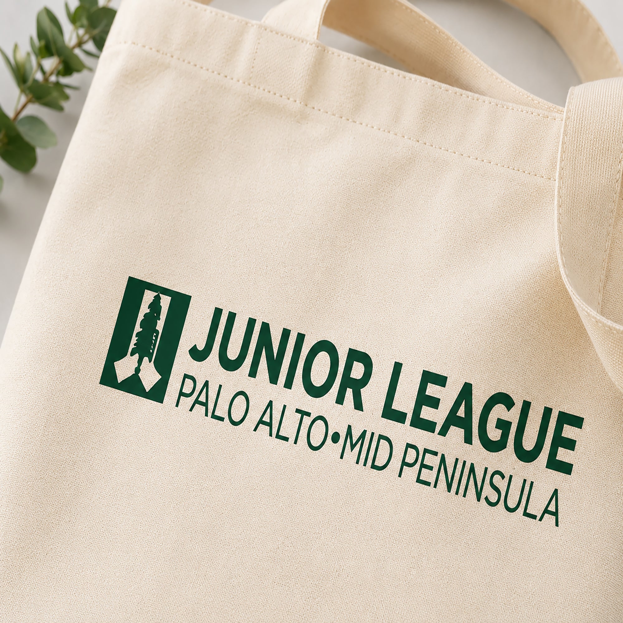 Natural tote bag with 'Junior League Palo Alto Mid Peninsula' logo on a light background