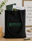 Black tote bag with Junior League logo on a table with a plant and books in the background