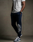 Person wearing navy 'Washington State Tigers' jogger pants with a white t-shirt against a gray background