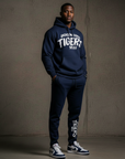 Person wearing a navy blue 'Tigers' hoodie and pants against a gray background