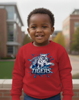 Child wearing a Jackson State Blue Blitz design on a red sweatshirt standing outdoors.