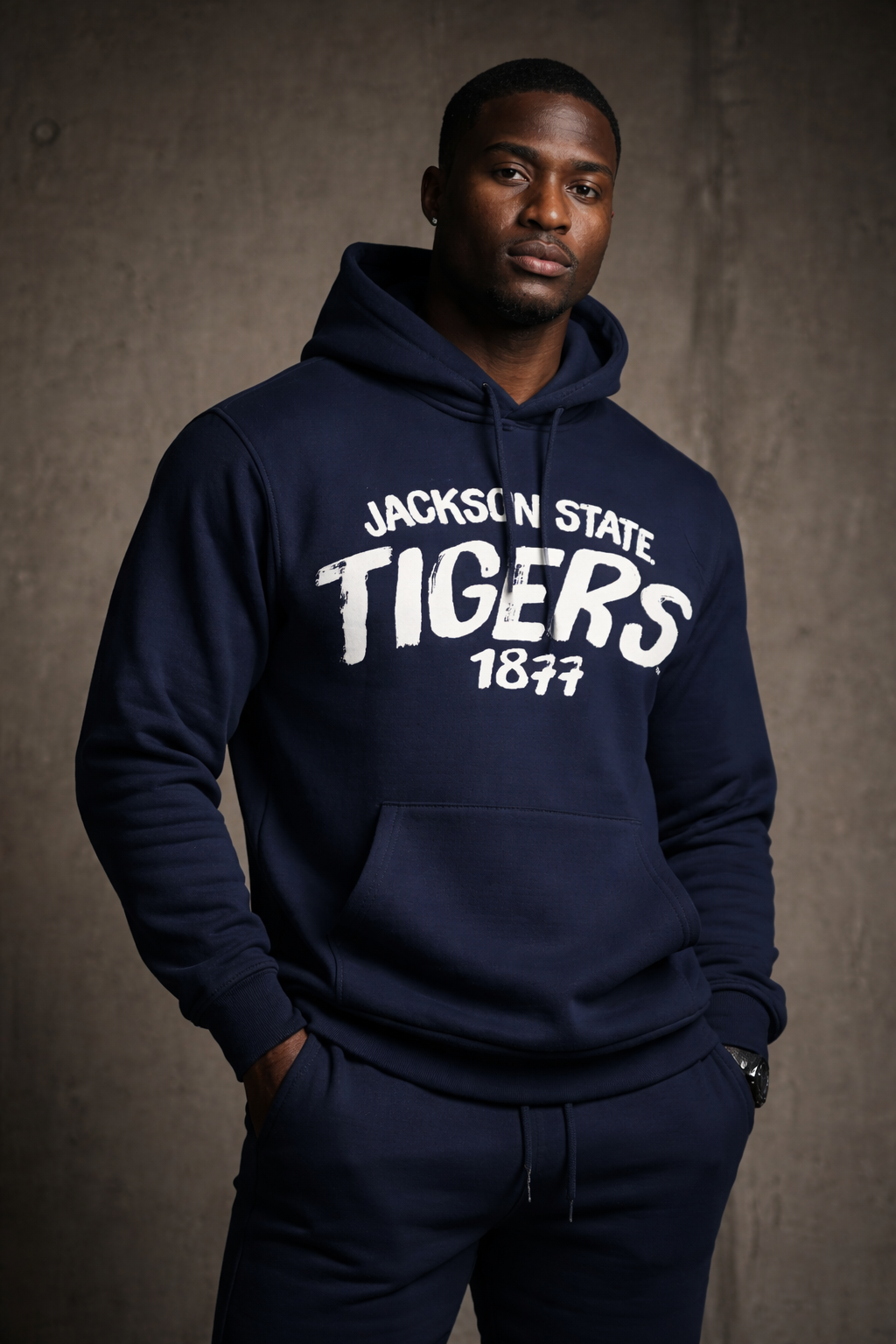Man wearing a navy hoodie with 'Jackson State Tigers 1877' text against a gray background