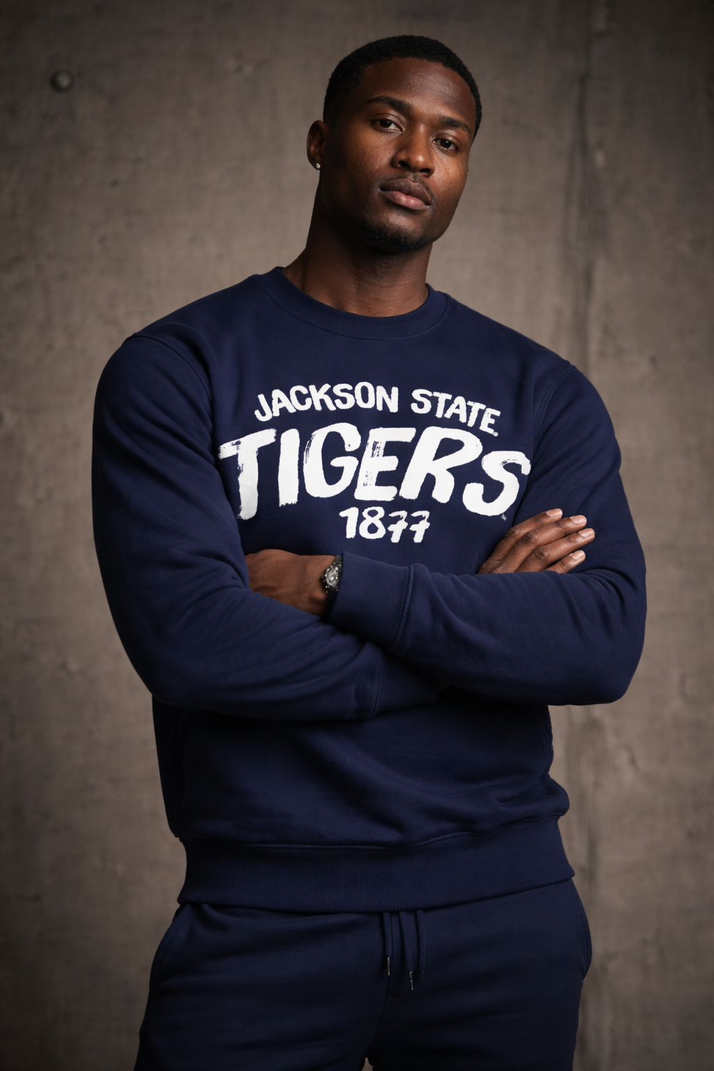 Man wearing a navy 'Jackson State Tigers' sweatshirt against a gray background