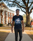 Black man wearing a navy blue Blue Blitz t-shirt on a college campus