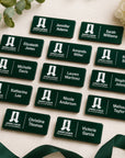 Flat lay of multiple laser engraved Junior League Palo Alto Mid Peninsula custom name badges personalized with member names arranged on neutral linen background with eucalyptus and white flowers
