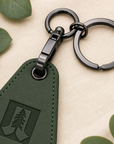 Close-up of black gunmetal swivel clip and keyring hardware on green engraved motel keychain