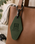 Close-up of black gunmetal swivel clip and keyring hardware on green engraved motel keychain